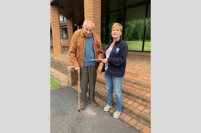 Sam handing over a cheque for a £800 donation, gathered from all guests at his birthday party instead of presents. The donation is being received by Lisa at Brecon Dial-a-Ride 